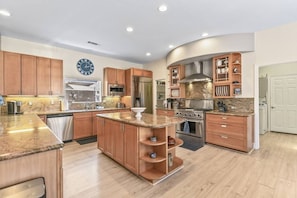 A modern kitchen with wooden cabinets, stainless steel appliances, and a central island.