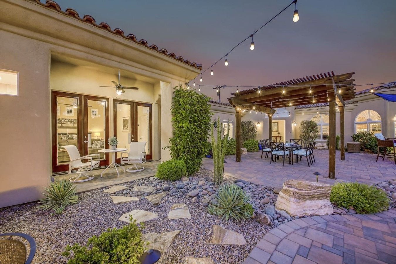 A patio area with outdoor seating, a pergola, and a well-maintained garden.