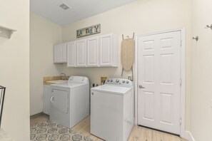 A laundry room with two front-loading washing machines, a drying rack, and a door. - California Paradise: #231868 3BR Pool, Spa, BBQ! (La Quinta)