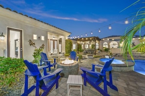 An outdoor patio area with blue Adirondack chairs, a fire pit, and a pool.