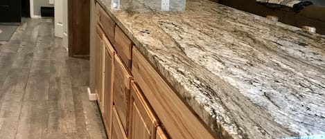 Una cocina con armarios de madera, encimera de granito y suelo de madera.