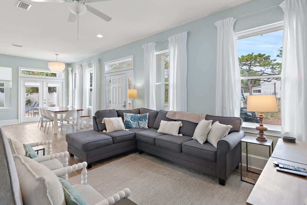 A living room with a sectional sofa, a dining table, and a ceiling fan.