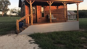 En træhytte med veranda, trapper og en stol.