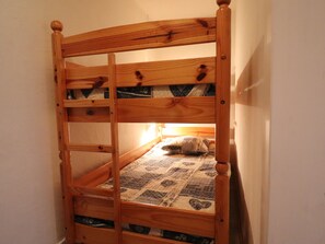 A wooden bunk bed with a quilted mattress and a pillow. - 2-Room Apartment with Mountain Area, Ideal for Families, Pets Allowed (Méribel)