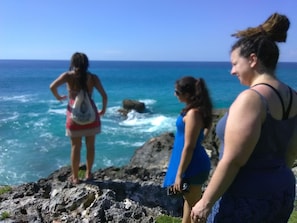 Three individuals standing on a rocky outcrop overlooking the ocean.