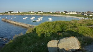 A coastal area with boats docked at a pier, a sandy beach, and houses in the background.