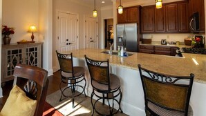 A kitchen with a central island, wooden cabinets, and pendant lighting. - Step into a spacious, luxury condo that has it all – a premiere location in the heart of the Historic District and floor-to-ceiling window views of the Savannah River, Talmadge Bridge and City Hall. 5th floor.Best river views in the building. (Savannah)