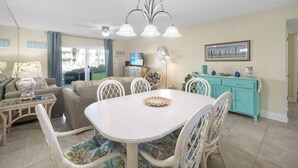A living room with a dining table, chairs, a sofa, and a television.