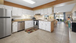 A modern kitchen with white cabinets, stainless steel appliances, and a central island.