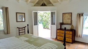 A bedroom with a bed, a dresser, a chair, and a window with curtains. - BOUGAINVILLIERS Very Private and Charming Villa With Sea View Close to the Beach (Anse de Marigot)