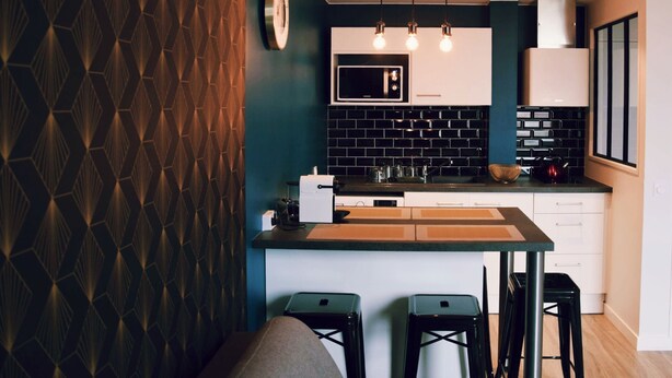 Eine moderne Küche mit einer Wand mit dunklem Muster, einer digitalen Uhr und einer Bar mit Hockern.