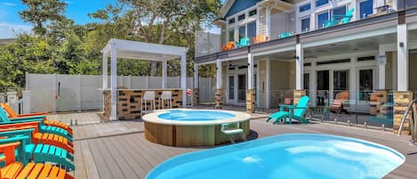 Un área de piscina con jacuzzi, mobiliario exterior y un porche cubierto.