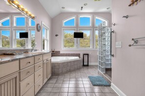 Une salle de bain spacieuse dotée d’une grande baignoire, d’une douche à l’italienne et d’un meuble-lavabo.