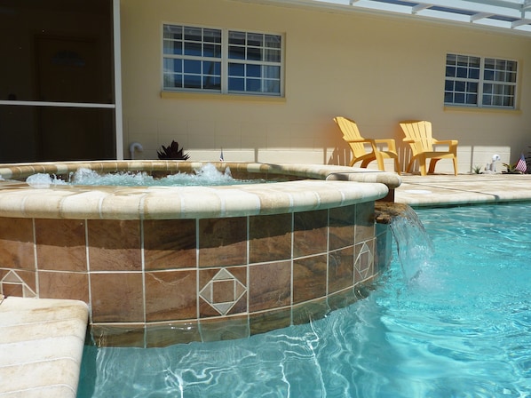 A swimming pool with a hot tub, outdoor chairs, and a building with windows in the background. - Save in Paradise: Attractive Autumn Rates (Cape Coral)