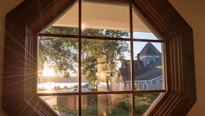 Una ventana hexagonal con vista a una casa y árboles.