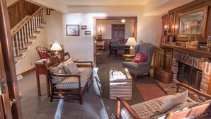 Una sala de estar acogedora con chimenea, muebles de madera y una escalera.