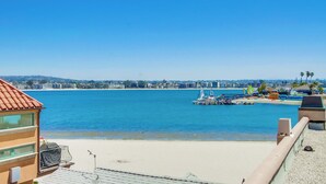 Blick auf die Küste mit Strand, einer Marina voller Boote und einer Stadt am Horizont.