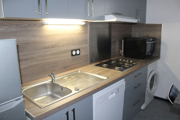 A modern kitchen with a stainless steel sink, a dishwasher, a microwave, and a stove.
