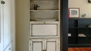 A white, multi-shelf cabinet with decorative items on top, positioned against a wall with a black trim. - Just blocks from UC, Simons, MSRI, Haas and Goldman Schools with great Bay views (Berkeley)