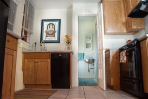 A kitchen with wooden cabinets, a dishwasher, a stove, and a framed picture of the Berkeley Repertory Theatre.