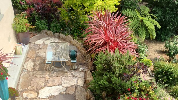 A stone patio with a table and chairs, surrounded by various potted plants and flowers. - Just blocks from UC, Simons, MSRI, Haas and Goldman Schools with great Bay views (Berkeley)