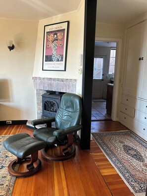 A living room with a fireplace, a framed artwork, and a leather chair.