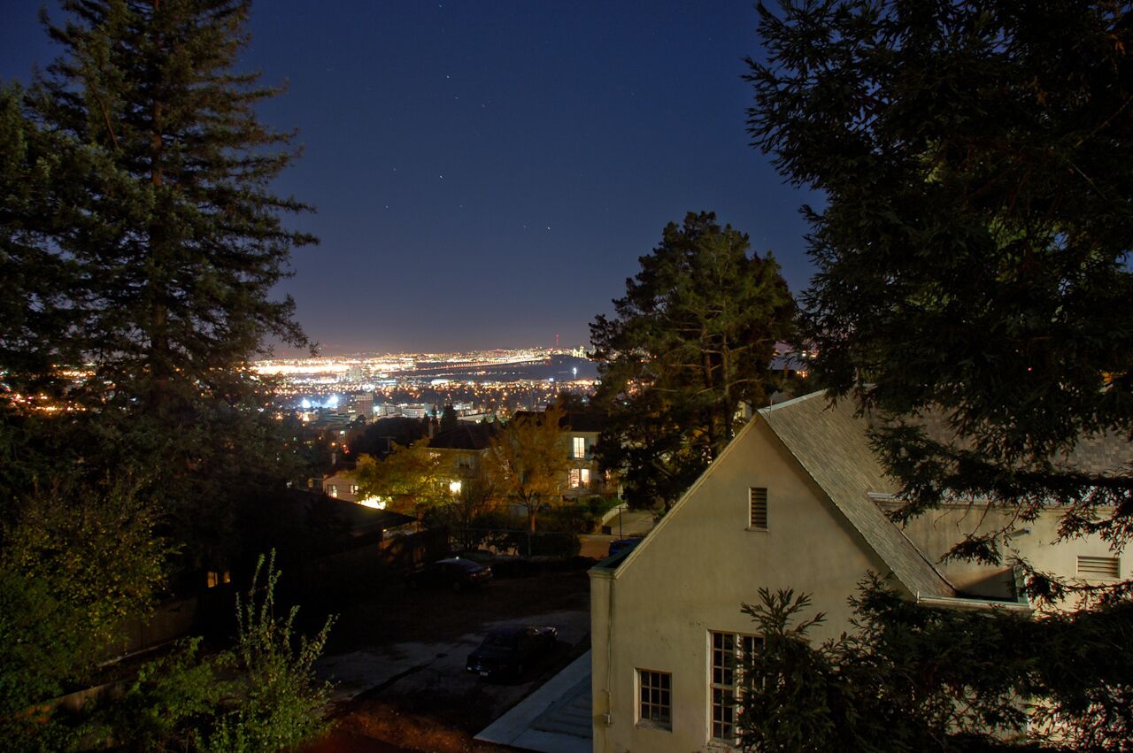 A nighttime view of a cityscape with a house in the foreground.