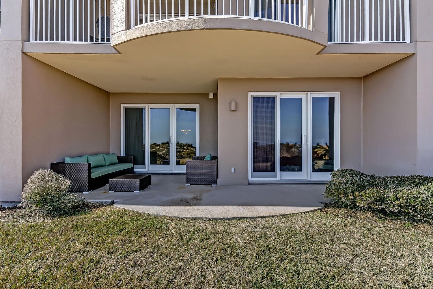 A modern building with a covered patio area featuring outdoor seating and sliding glass doors.