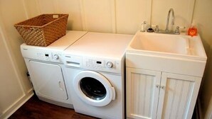 Un espace buanderie compact comprenant un lave-linge, un sèche-linge et un évier.