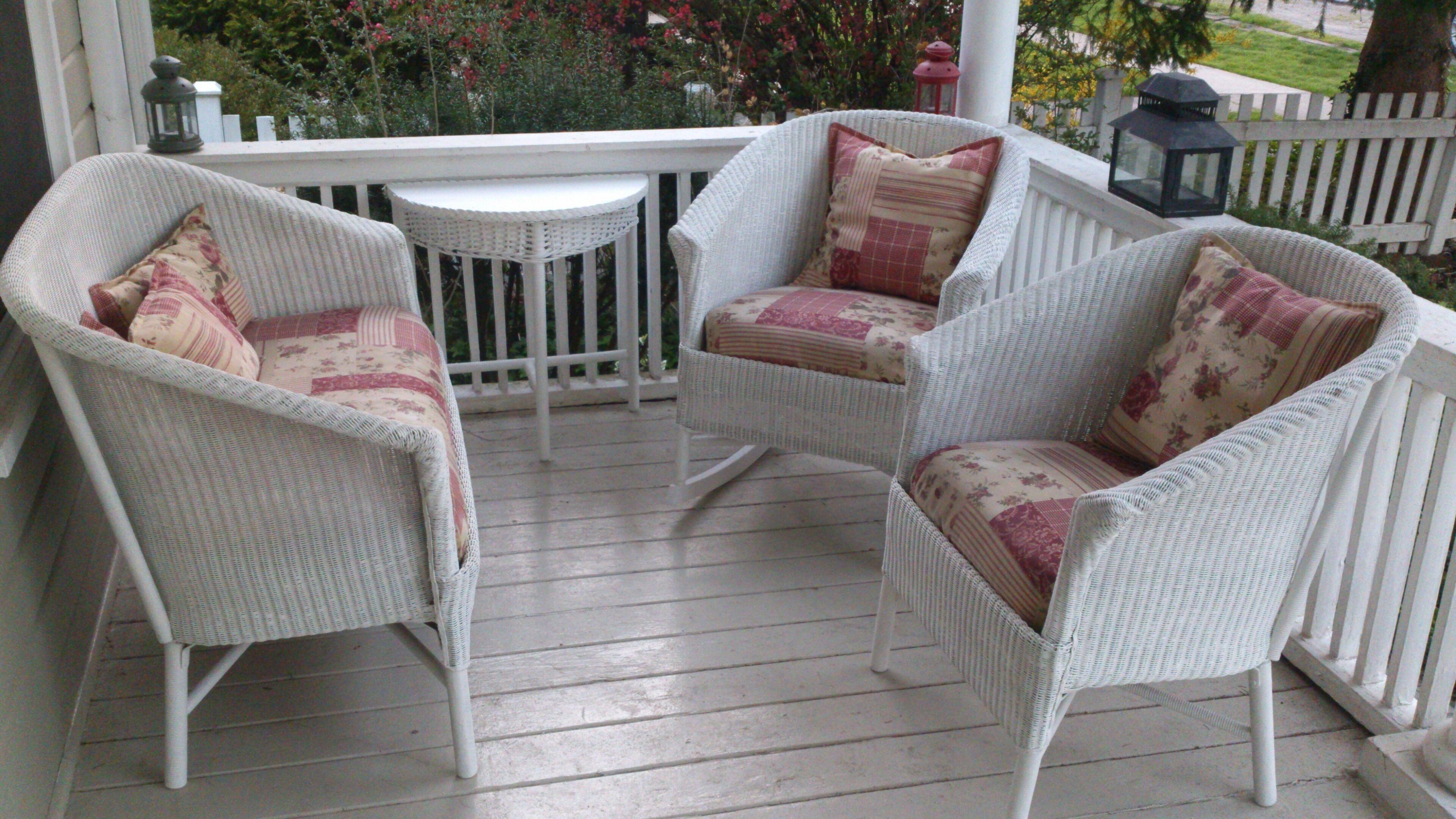 A porch with wicker chairs and a small table.