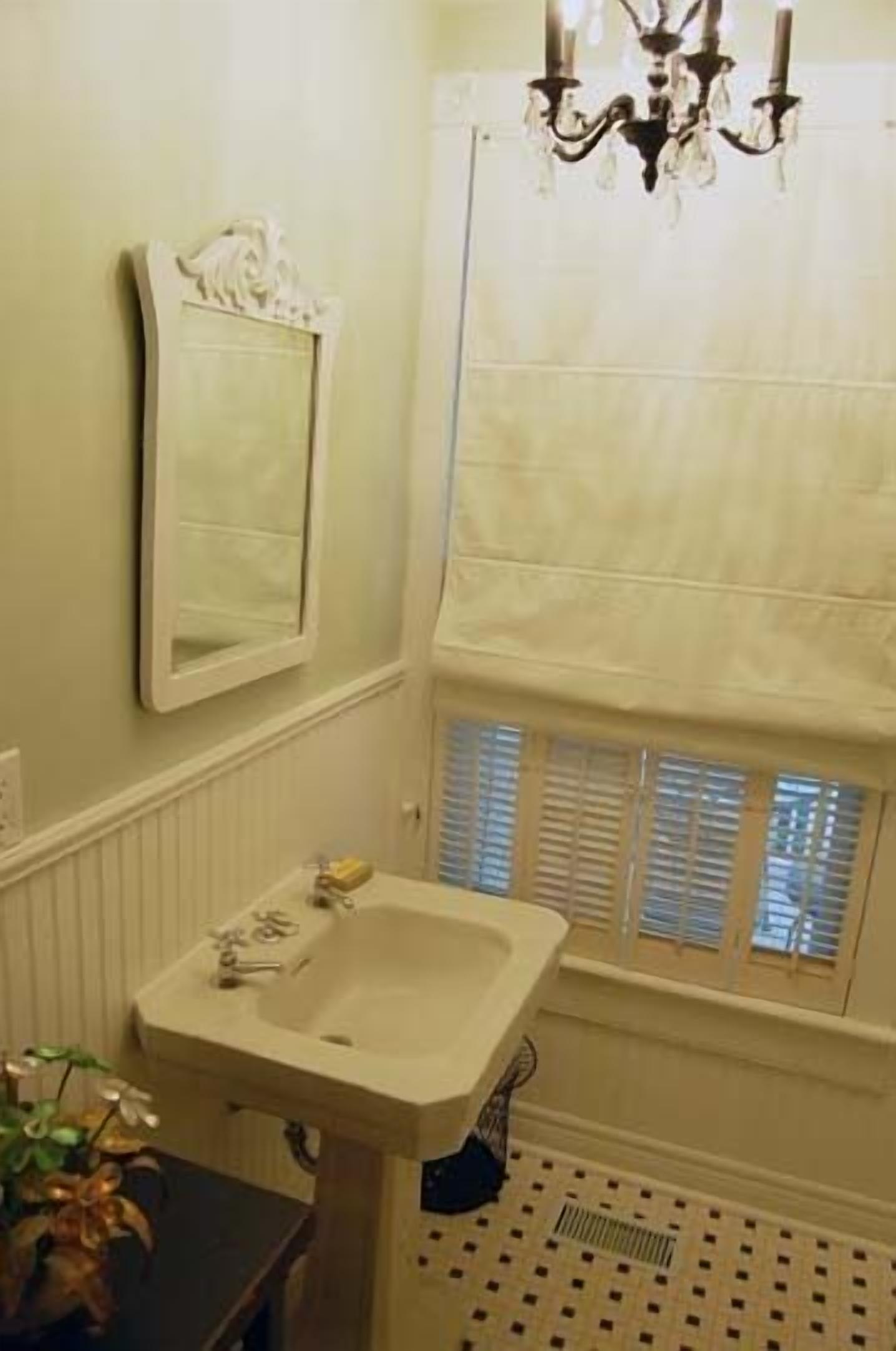 A bathroom with a sink, mirror, and window with blinds.