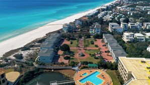 An aerial view of a coastal resort with a swimming pool, beachfront, and multiple buildings. - Beautifully Decorated Gulf Front Townhome In Private Gated Community (Santa Rosa Beach)