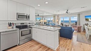 A modern kitchen with white cabinets, stainless steel appliances, and a large island. - Beautifully Decorated Gulf Front Townhome In Private Gated Community (Santa Rosa Beach)