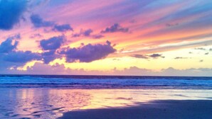 Une plage au coucher du soleil, avec des nuages.