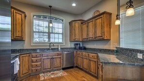 A kitchen with wooden cabinets, granite countertops, a dishwasher, and a window with blinds. - LARGE OR MULTI FAMILY ALERT- lakeviews-sleeps 9-next to pools- SDC (Branson)