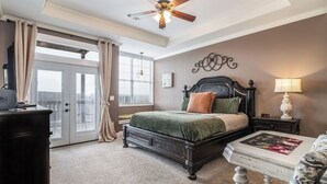 A bedroom with a bed, a ceiling fan, a nightstand, a lamp, a dresser, and a window with curtains. - LARGE OR MULTI FAMILY ALERT- lakeviews-sleeps 9-next to pools- SDC (Branson)
