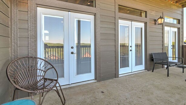 A covered patio area with a sliding glass door entrance, a wicker chair, and a bench. - LARGE OR MULTI FAMILY ALERT- lakeviews-sleeps 9-next to pools- SDC (Branson)