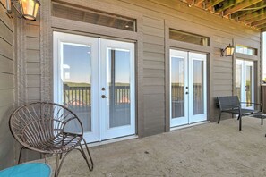 A covered patio area with a sliding glass door entrance, a wicker chair, and a bench. - LARGE OR MULTI FAMILY ALERT- lakeviews-sleeps 9-next to pools- SDC (Branson)