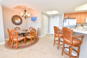 A dining area with a round table and chairs, a chandelier, and a decorative mirror.