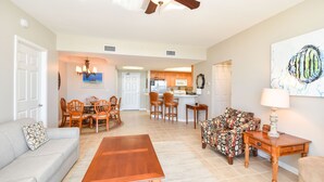 A spacious living room with a dining area, kitchen, and a ceiling fan. - Fully equipped open-concept condo w/private balcony in Destin! 🌺 (Destiin)