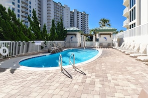 A pool area with a no diving sign, lounge chairs, and a building with a dolphin mural.