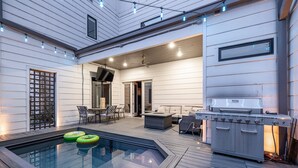 En moderne udendørs terrasse med jacuzzi, siddepladser og grill.
