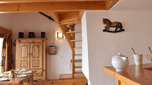 A wooden interior with a dining table set for four, a wooden cabinet, and a wall-mounted horse decoration. - Cozy 2-Room Mezzanine Apartment for 6 in Méribel Center, 200m from Slopes (Méribel)