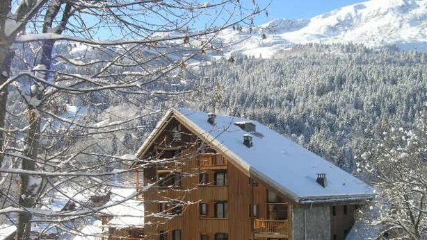 A wooden chalet with multiple balconies, surrounded by snow-covered trees and mountains in the background. - Cozy 2-Room Mezzanine Apartment for 6 in Méribel Center, 200m from Slopes (Méribel)