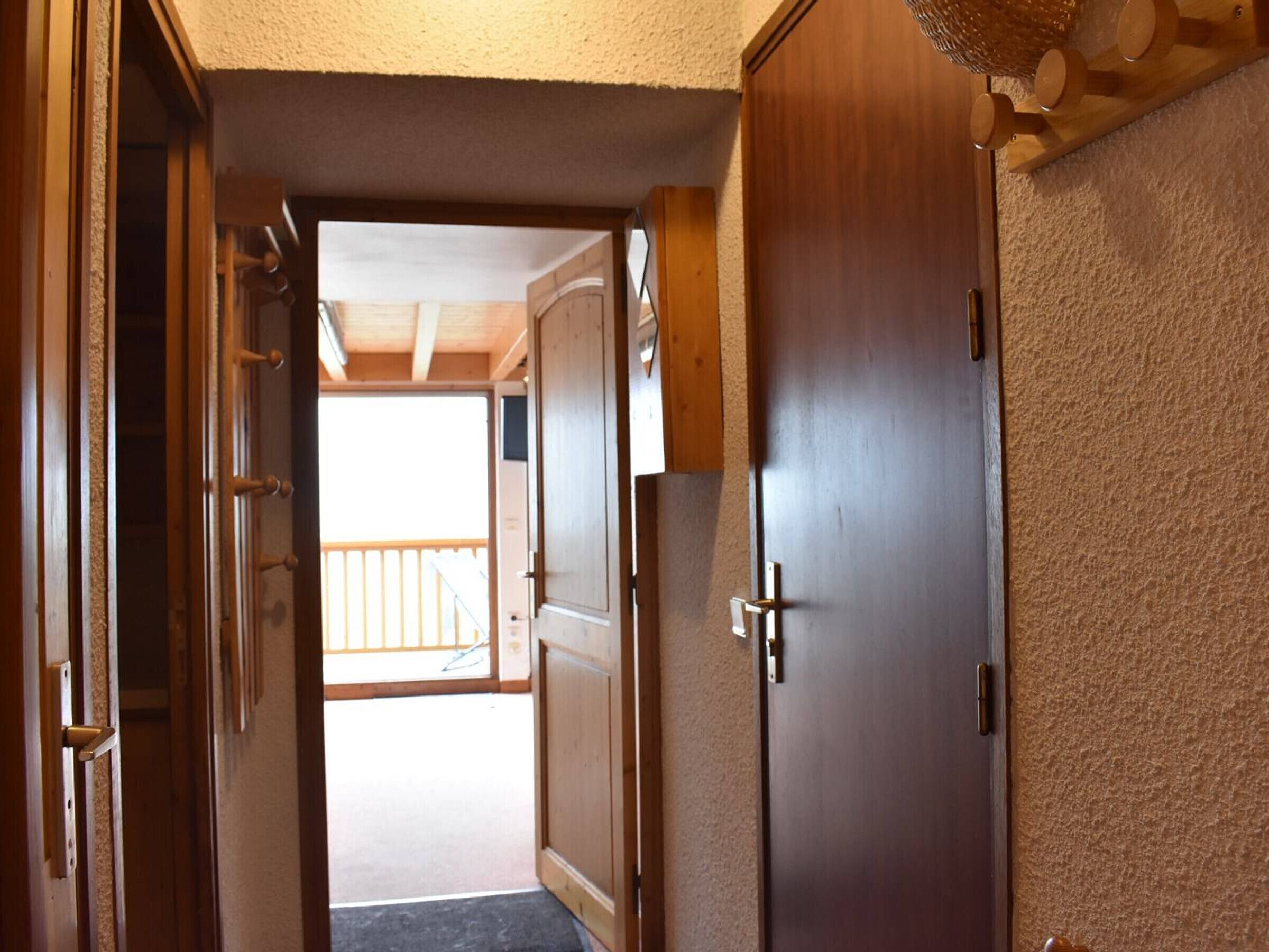 Un couloir avec des portes en bois et une vue sur un balcon extérieur.