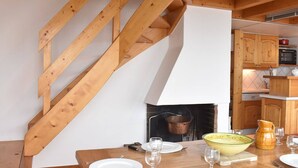 A wooden staircase leading to a dining area with a table set for four, a fireplace, and wooden cabinets. - Cozy 2-Room Mezzanine Apartment for 6 in Méribel Center, 200m from Slopes (Méribel)