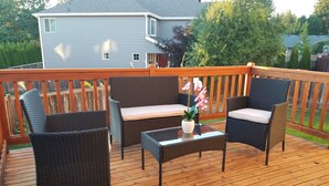 Eine Terrasse mit Korbmöbeln, einem Glastisch und einem Blumentopf.