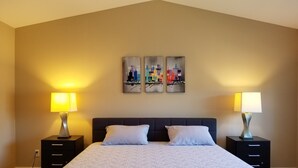 Ein Schlafzimmer mit einem großen Bett, zwei Nachttischen und drei an der Wand befestigten Bildern.