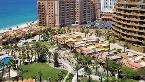 Ett semesterkomplex med flera byggnader, en pool och en strand.