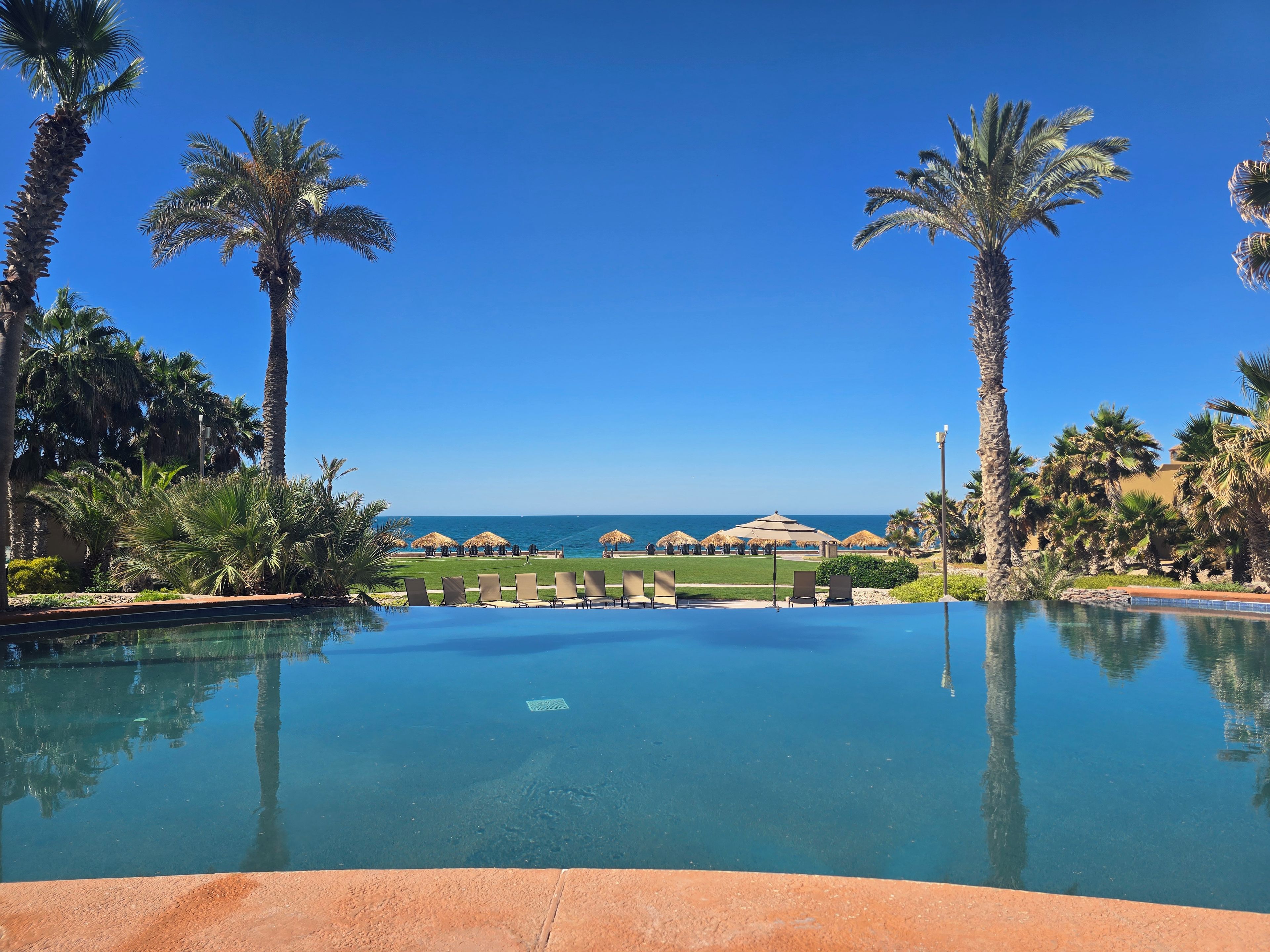 A clear blue sky, a swimming pool, and a view of the ocean.